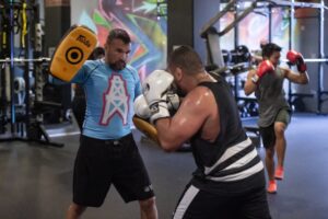 Two men in a gym with boxing gloves.
