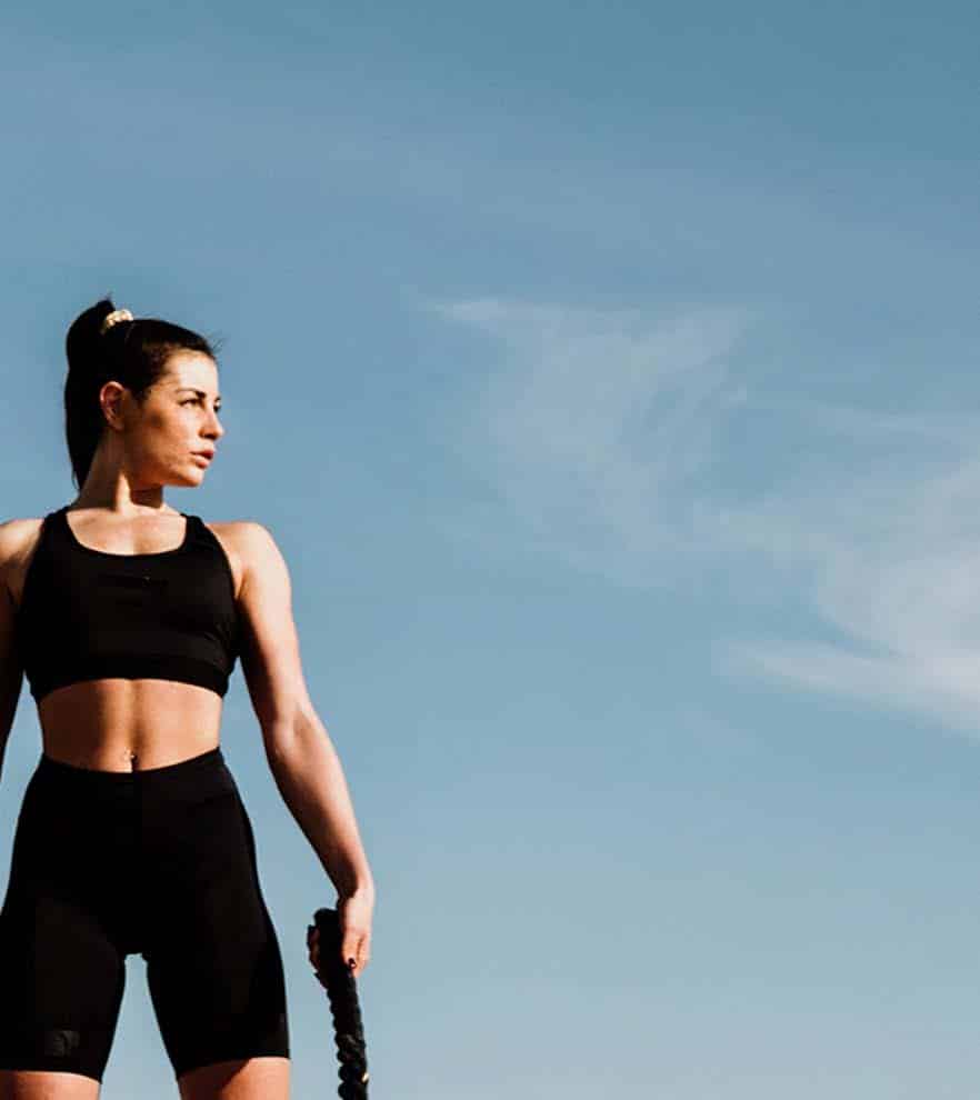 A woman is holding a skipping rope in front of a blue sky.