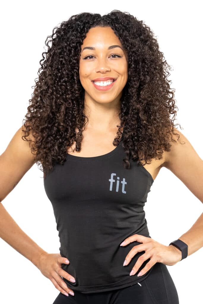 A woman with curly hair wearing a black tank top and leggings.