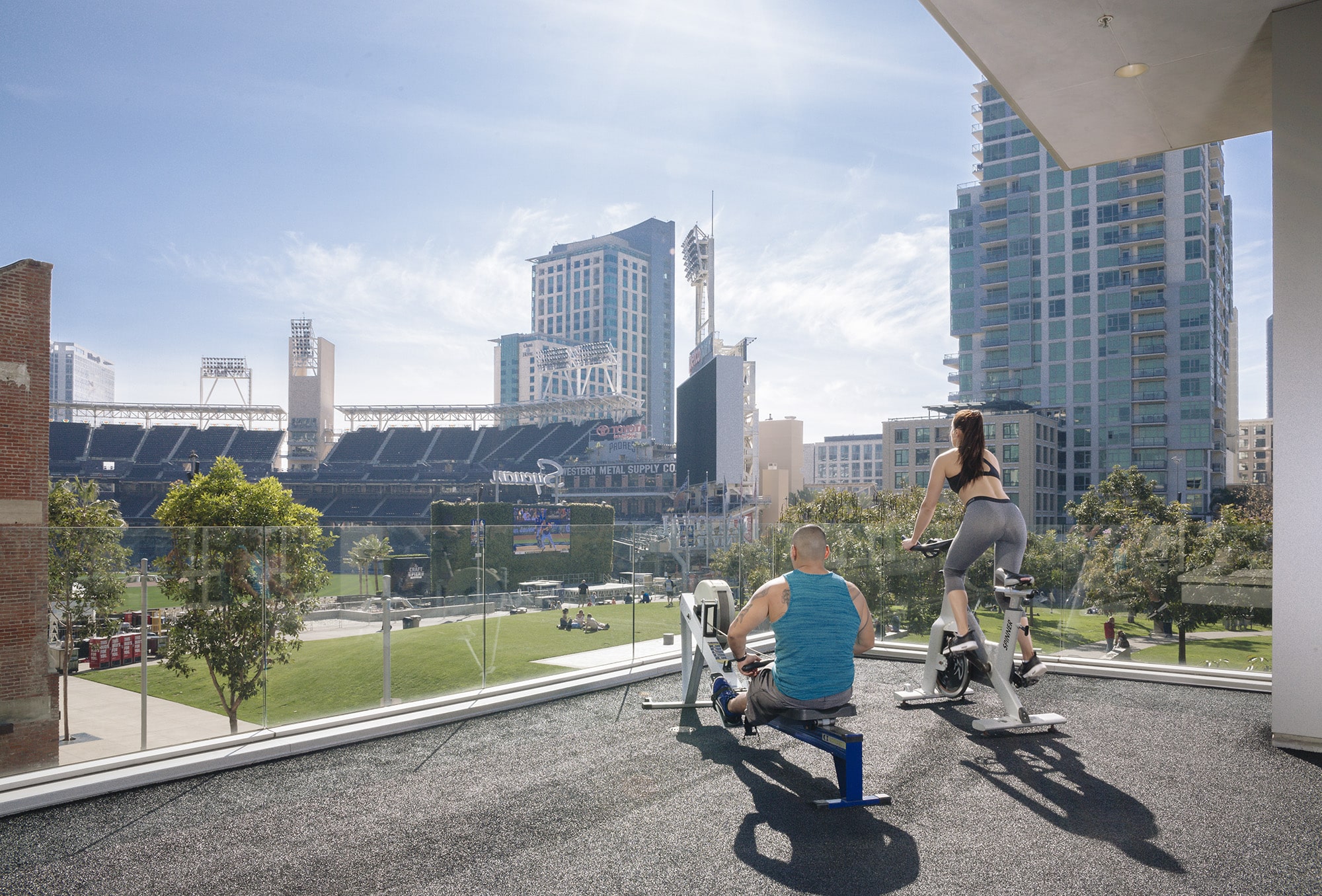 Two people on exercise bikes in a gym with a view of a city.