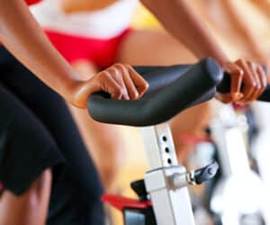 A group of people riding stationary bikes in a gym.