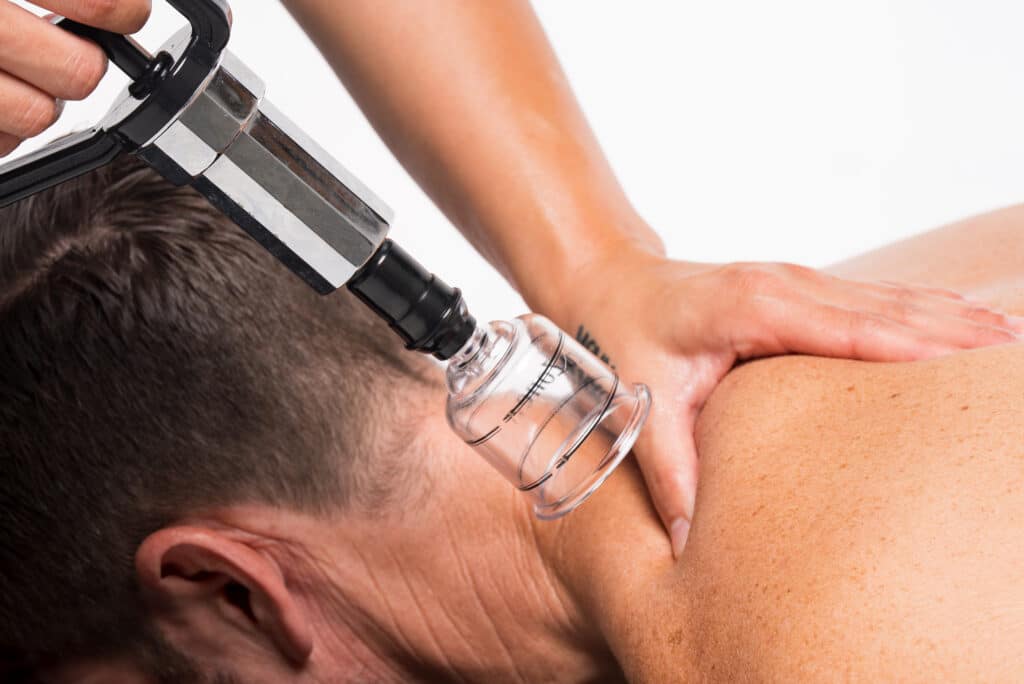 A person receiving shockwave therapy on their shoulder from a practitioner.