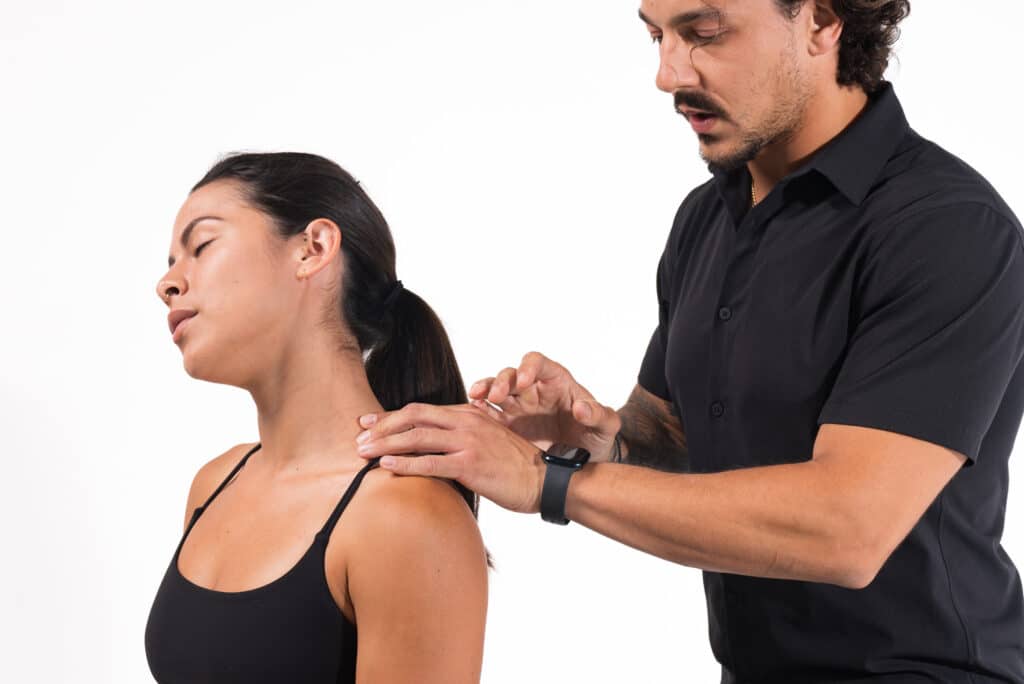 Massage therapist applying shoulder massage to a relaxed female client.