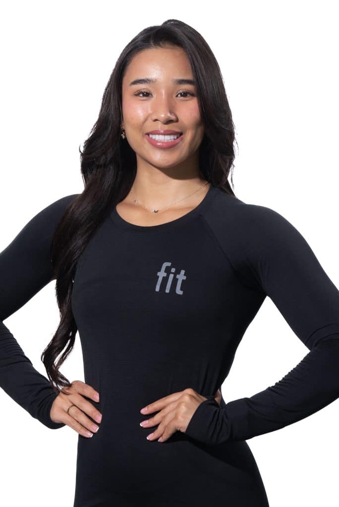 A person with long dark hair wearing a black long-sleeve shirt with the word "fit" printed on it stands against a white background.