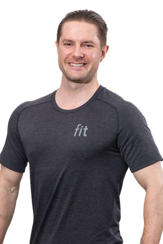 A man in a dark gray athletic T-shirt with "fit" printed on it, smiling against a white background.