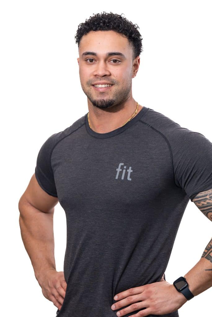 A man wearing a black t-shirt with "fit" written on it poses with hands on hips. He has curly hair and is wearing a smartwatch.