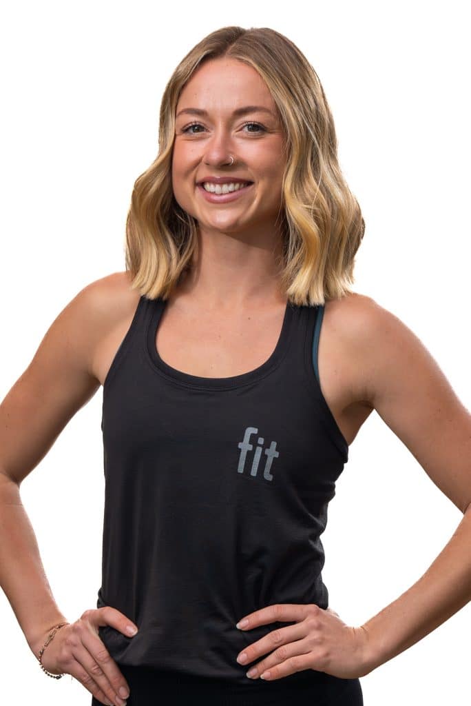 A person with shoulder-length blonde hair is smiling, wearing a black tank top with "fit" printed on it.