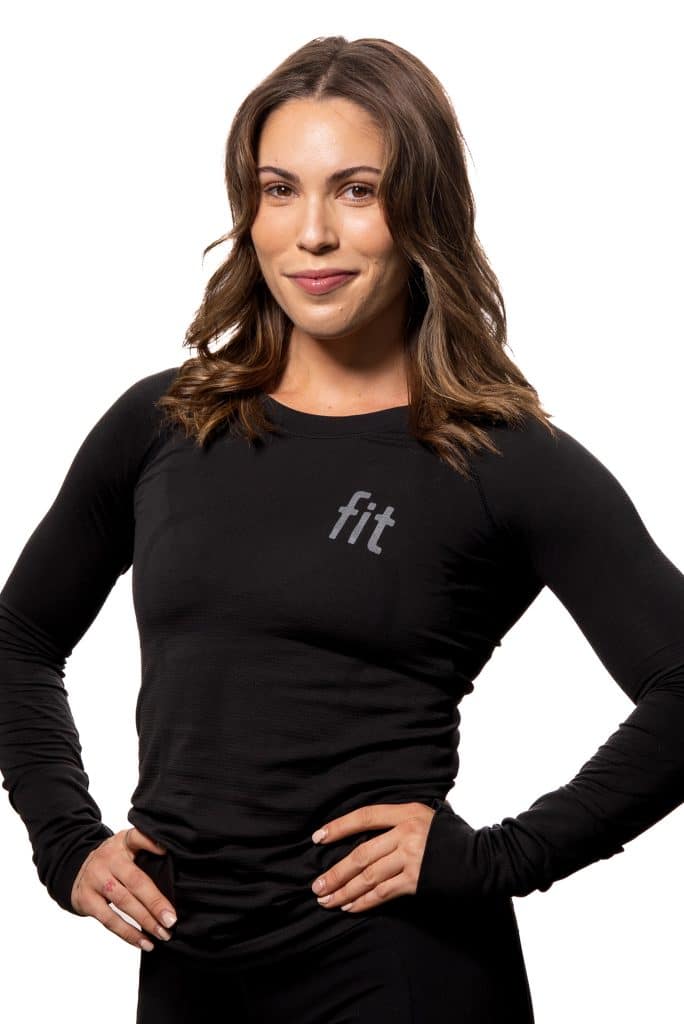 A person in a black long-sleeve shirt with the word "fit" on the chest stands with hands on hips, smiling, against a white background.